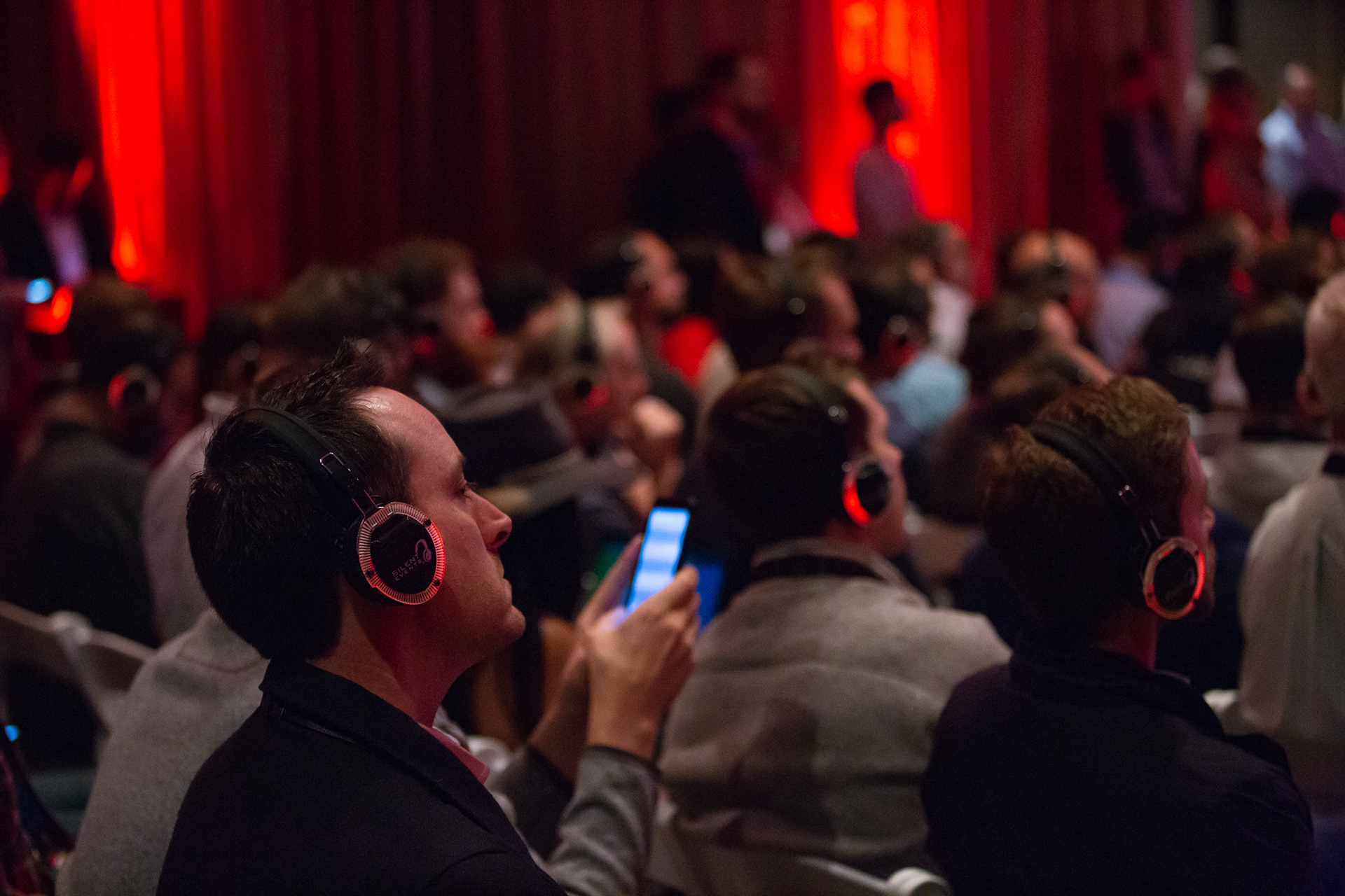 Audience wearing illuminated red headphones at an enterprise conference event